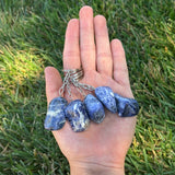 Hand holding Sodalite Keychains against a grass background