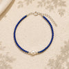 Blue beaded bracelet with a pearl on a beige fabric background