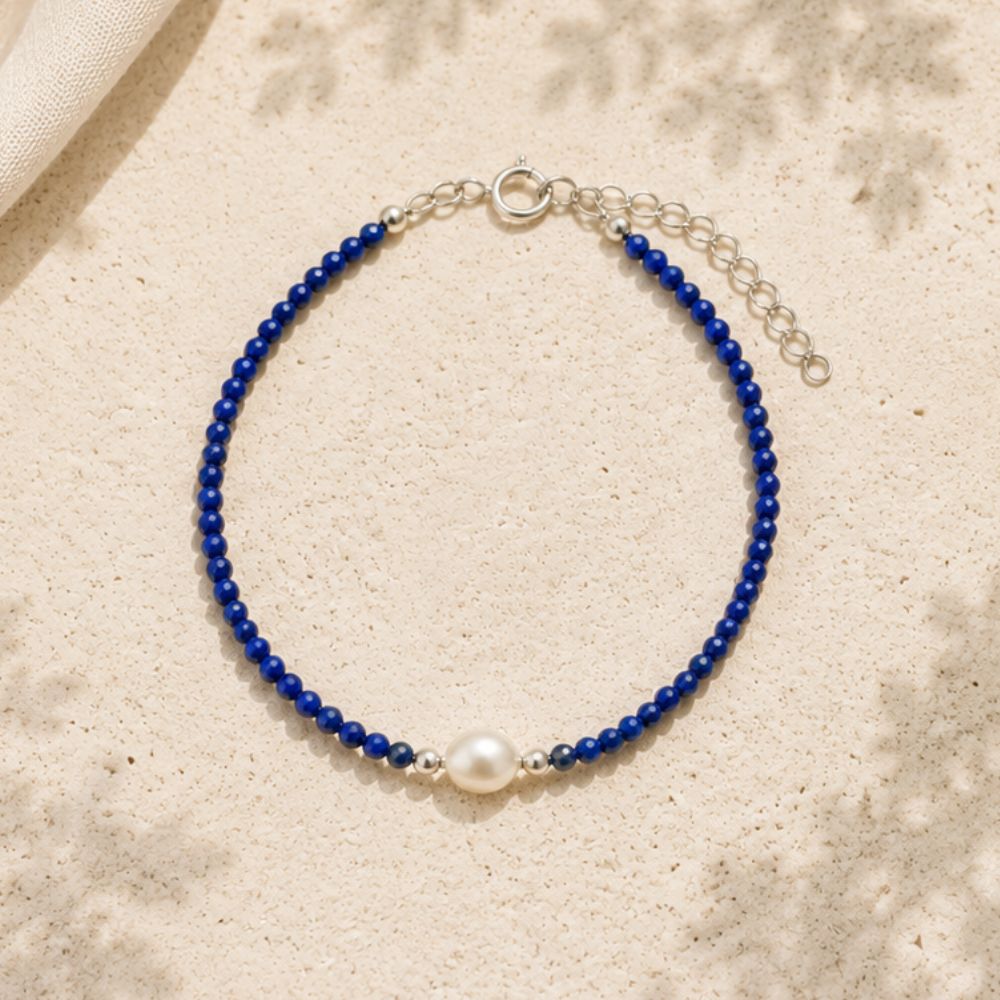 Blue beaded bracelet with a pearl on a beige fabric background