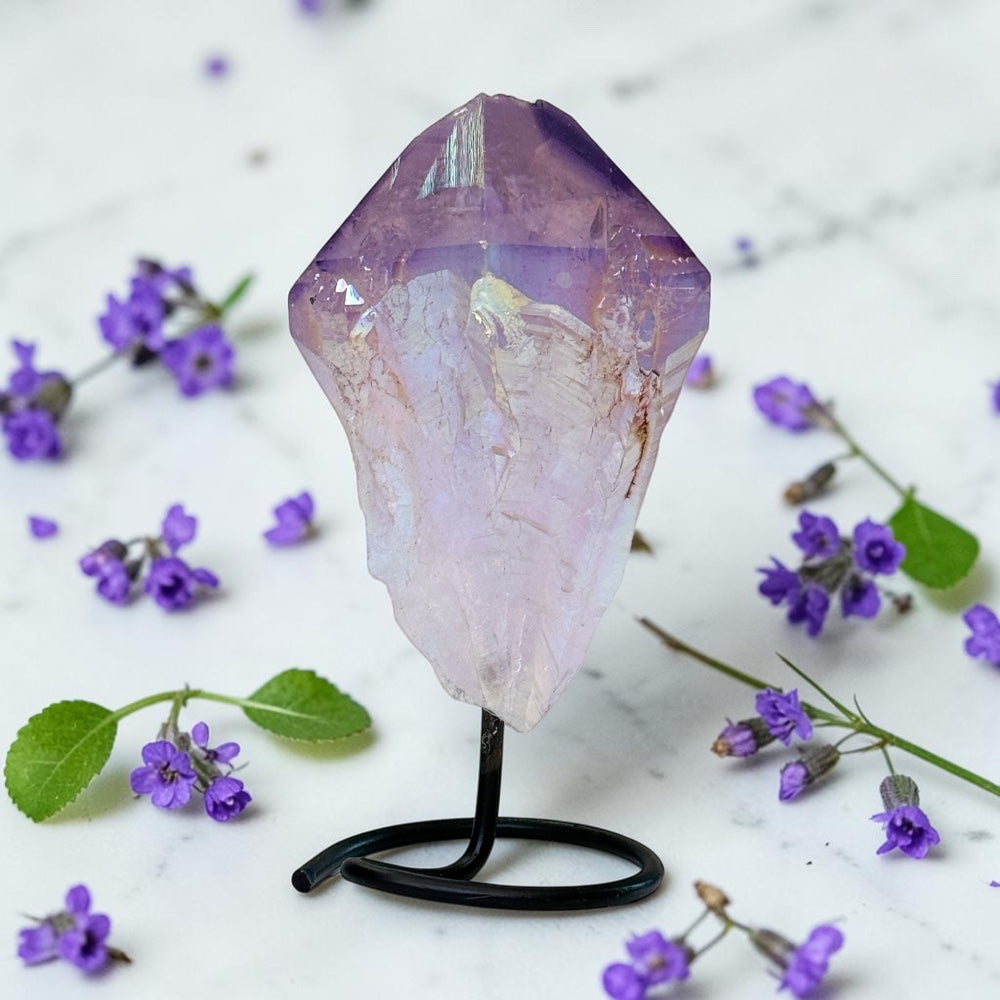 Crystal on a stand with purple flowers on a light background