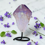 Crystal on a stand with purple flowers on a light background