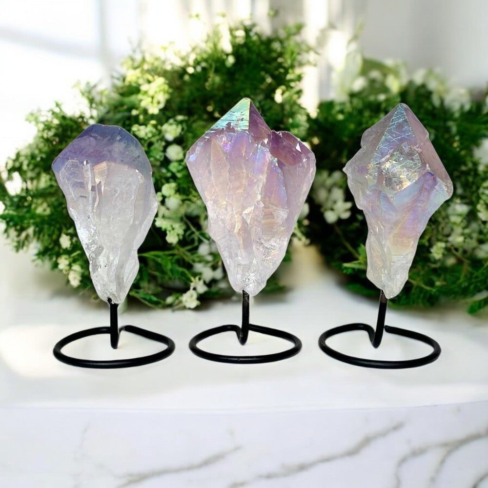 Three crystal rock formations on stands with a blurred greenery background