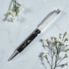 Pen with decorative elements on a light gray surface with white flowers