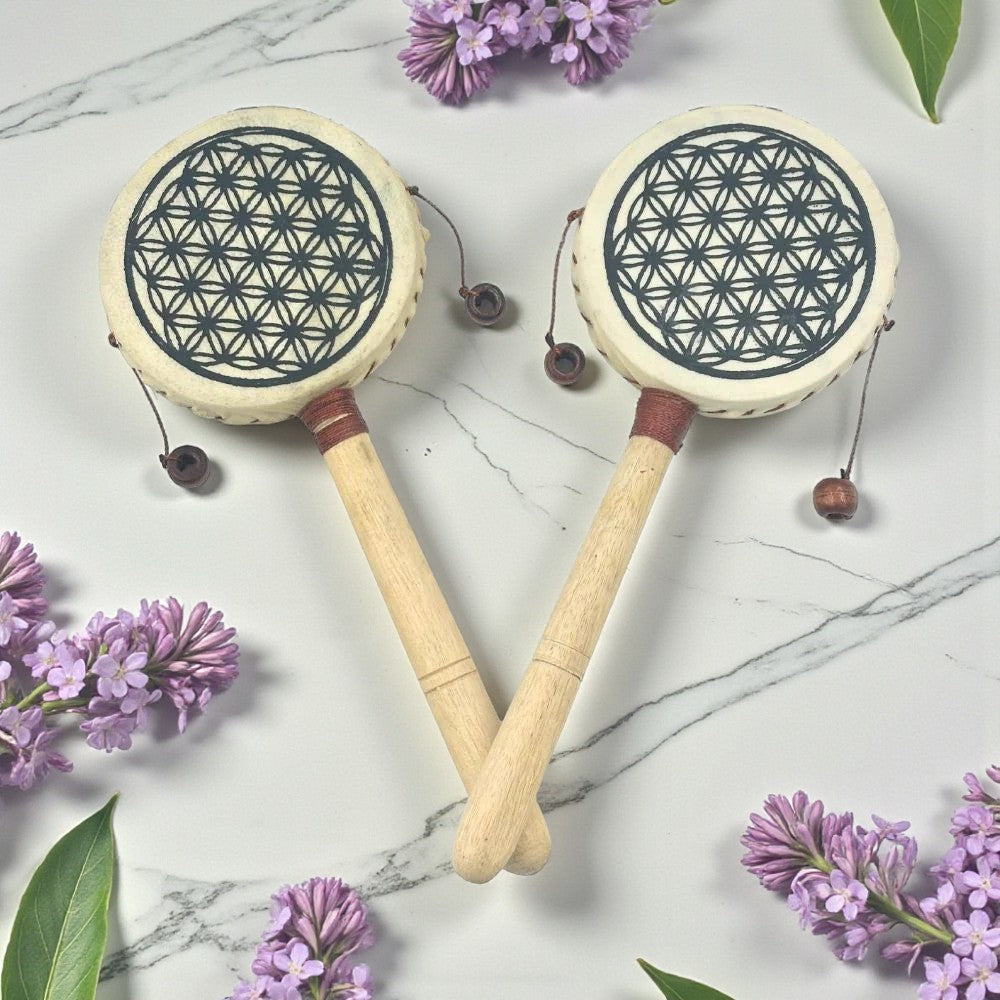 Two Hand Drum with floral designs on a marble surface with purple flowers.