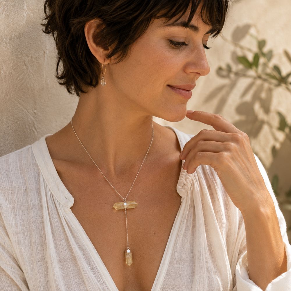 Woman with short dark hair wearing a citrine double crystal Y necklace with a silver chain.