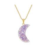 A gold chain necklace with a crescent moon pendant covered in iridescent glitter, shown against a plain white background.