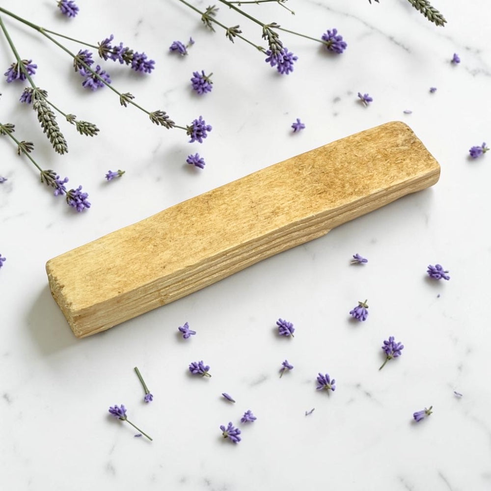 Palo Santo Single Stick on a marble surface with scattered lavender flowers