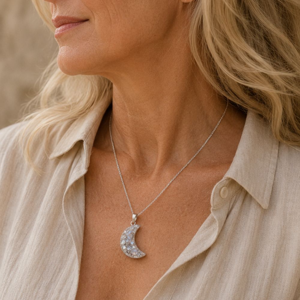 Woman wearing a silver necklace with a crescent moon pendant.