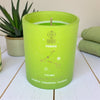 Green candle with 'Pisces' design on a white surface with a plant and towel in the background