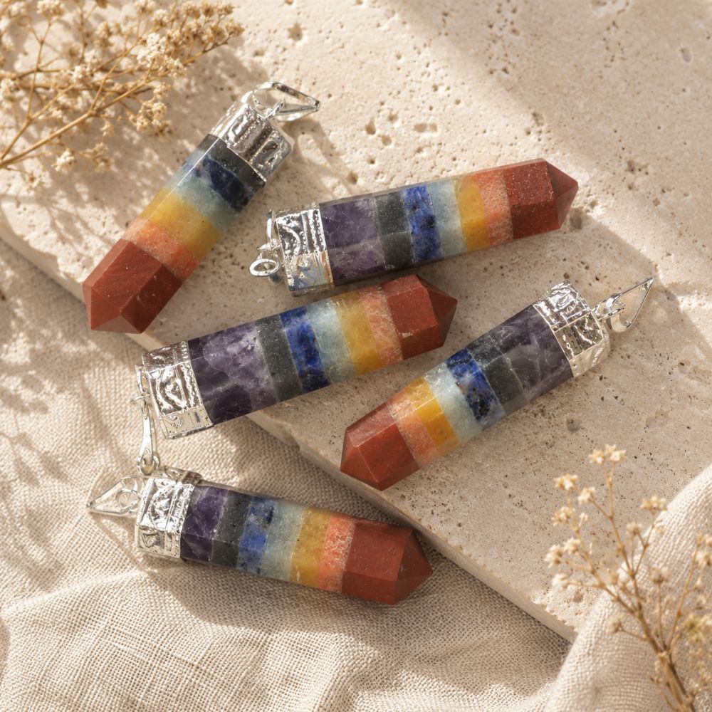 Chakra point pendants displayed on a natural stone surface with soft linen and dried botanicals.