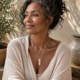 Woman wearing a silver-plated necklace with a rose quartz point pendant.