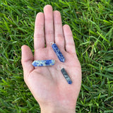 Sodalite crystal point pendants displayed in the palm of a hand for size reference.