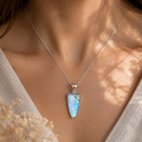 Necklace with a Moonstone pendant worn by a person, with a neutral background