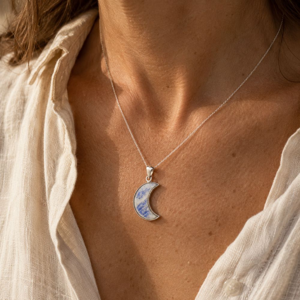 Rainbow moonstone crescent moon sterling silver pendant worn on a necklace.