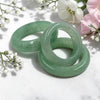Three green aventurine rings on a white marble surface with flowers in the background