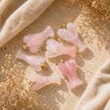 Rose Quartz Angel Pendants displayed on a neutral stone background with soft linen and dried botanicals.