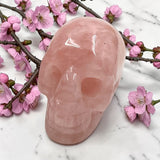 Pink crystal skull with cherry blossoms on a marble surface