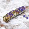 White sage with purple flowers on a wooden surface