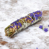 White sage with purple flowers on a wooden surface