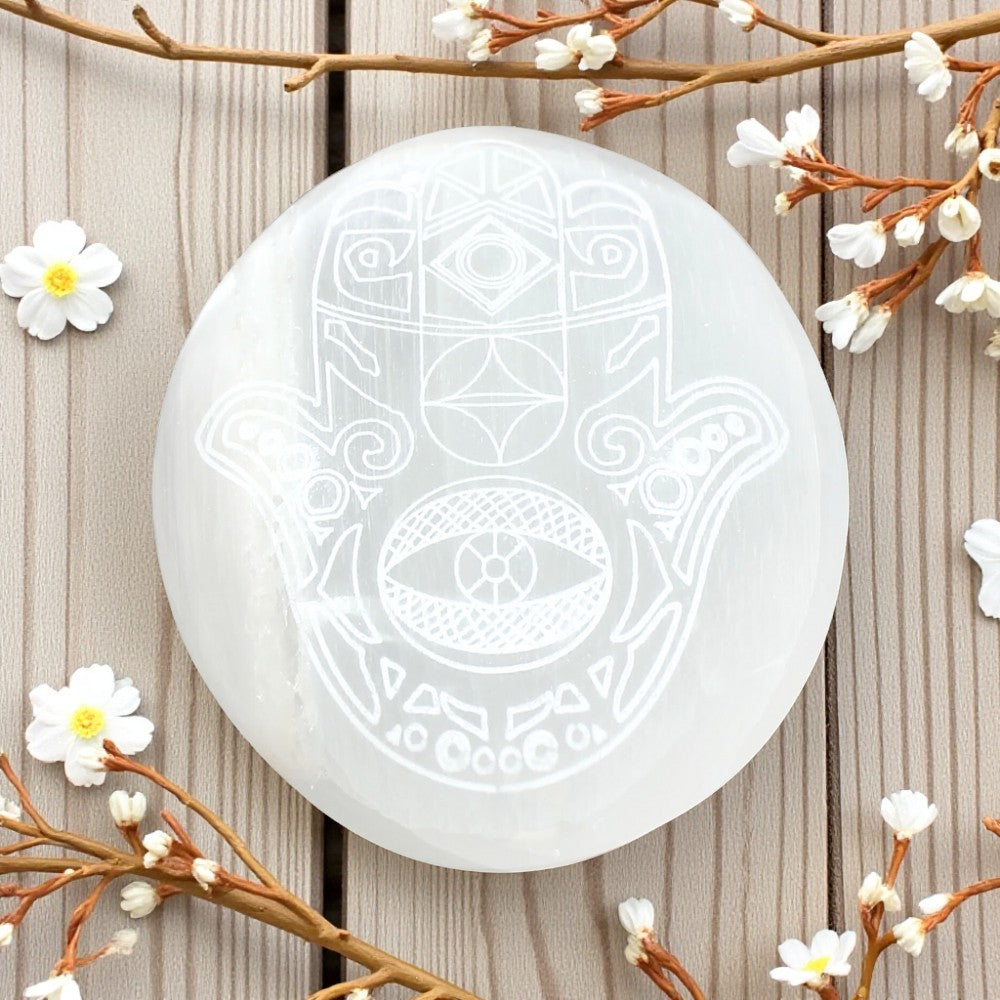 Selinite palmstone with geometric patterns on a wooden surface with floral elements