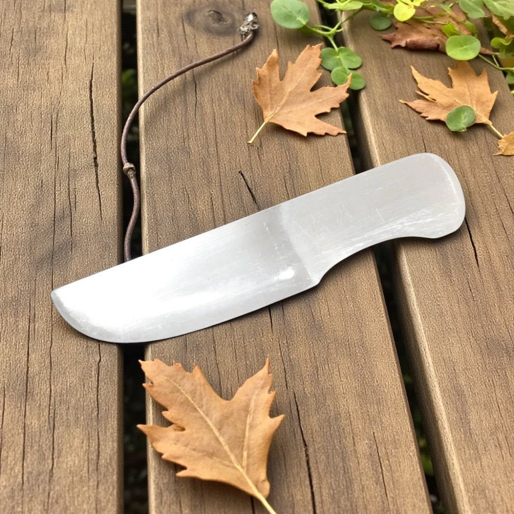 Selenite knife on a wooden surface with leaves