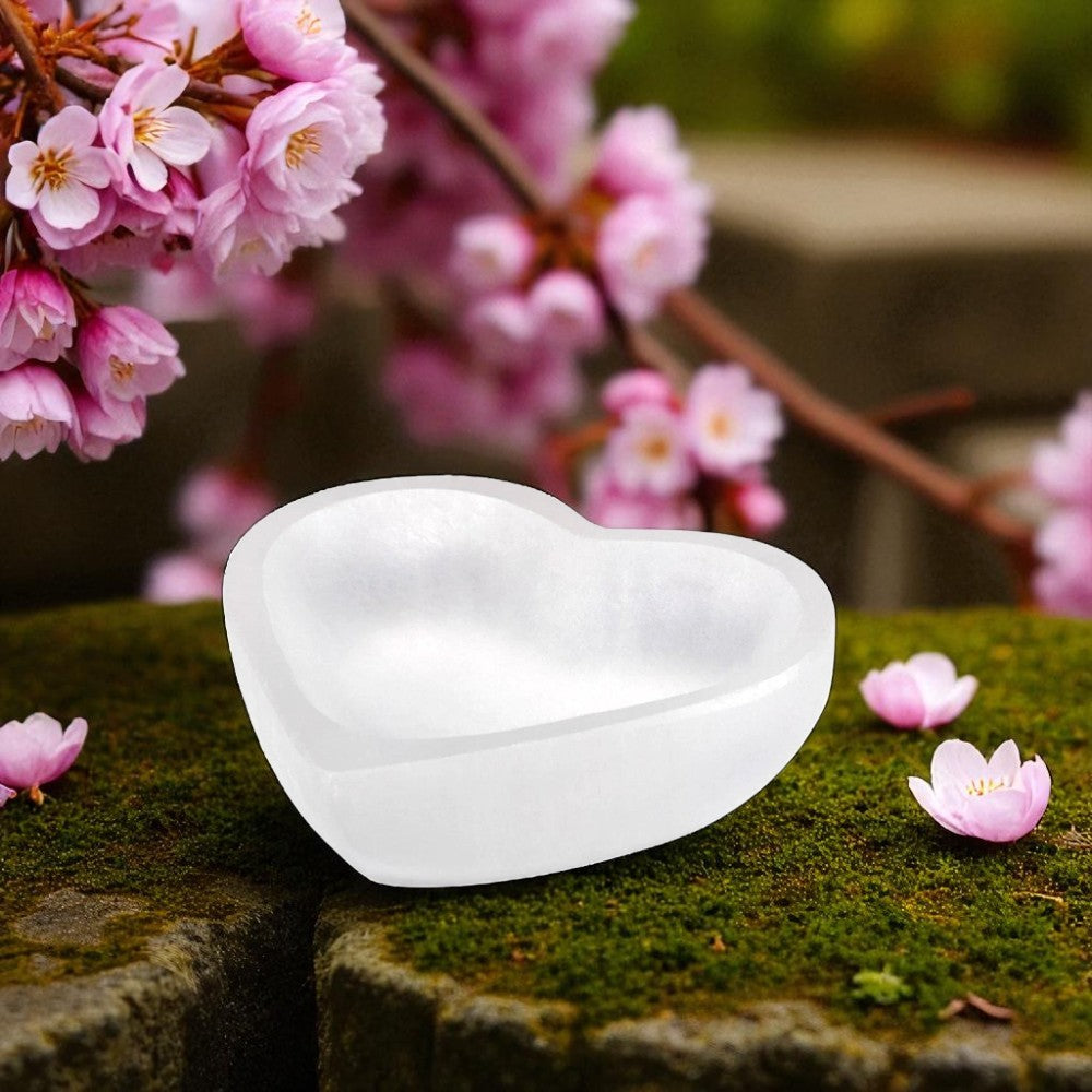 Heart-shaped white object on a stone surface with cherry blossoms in the background