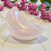 Aura Rose Half Moon Trinket Dish on a marble surface with pink roses in the background