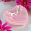 Aura Rose Quartz Heart Trinket Dish on a white surface with pink flowers.