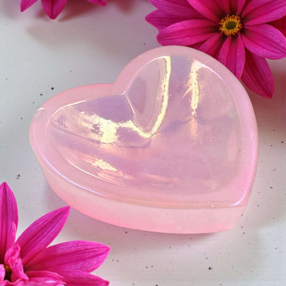 Aura Rose Quartz Heart Trinket Dish on a white surface with pink flowers.