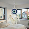 Dreamcatcher with feathers hanging above a bed in a room with large windows.
