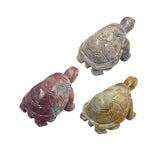 Three small carved soapstone turtles in different stone colors, shown on a plain white background.