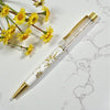 Decorative pen with floral design on a marble surface with yellow flowers.