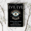 Book cover of 'The Evil Eye' on a marble surface with decorative branches.