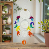 Decorative dreamcatcher with colorful feathers on a wooden surface, blurred indoor background
