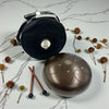 Brown Steel Tongue Drum - 10" on a marble surface with dried flowers and sticks.