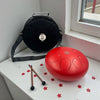 Red Steel Tongue Drum - 10" on a white surface near a window