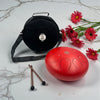 Red Steel Tongue Drum - 12" with carrying case, drumsticks, and red flowers on a marble surface