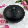 Black tongue drum on a marble surface with pink flowers