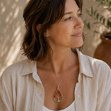 Woman wearing a Tree of Life pendant with carnelian gemstone chips and a silver wire tree design on a delicate necklace. 