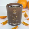 Candle labeled 'Virgo' with star constellation design, surrounded by orange slices on a white background