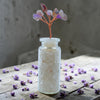 Wishing Jar Spirituality - Clear Quartz with scattered flowers on a wooden surface.