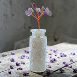 Wishing Jar Spirituality - Clear Quartz with scattered flowers on a wooden surface.