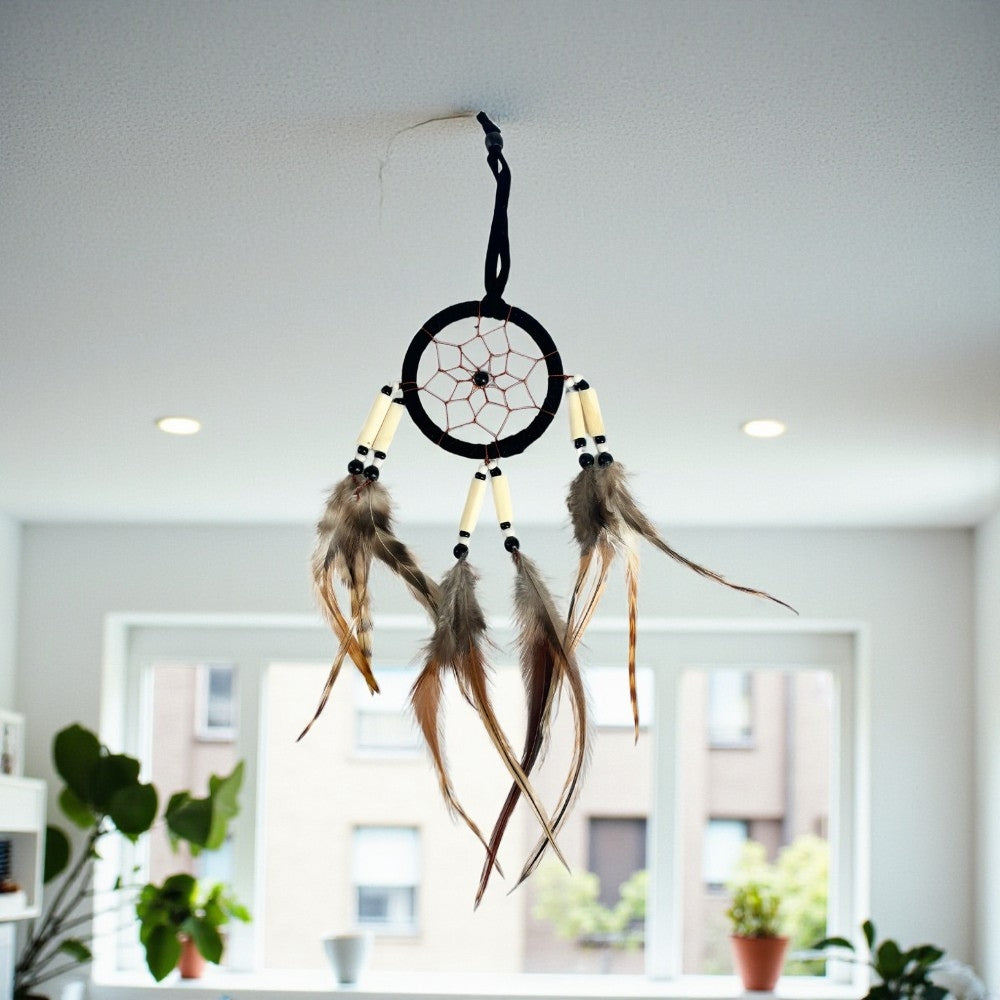 Dreamcatcher with feathers hanging against a blurred indoor background