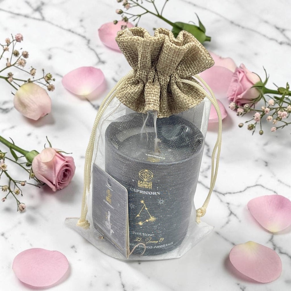 Candle in a decorative bag with pink flowers on a marble surface