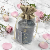 Candle in a decorative bag with pink flowers on a marble surface