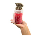 Hand holding a red candle in a clear bag with a drawstring, against a white background