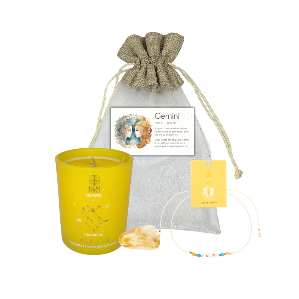 Yellow candle with 'Gemini' design, gray drawstring bag, and necklace on a white background