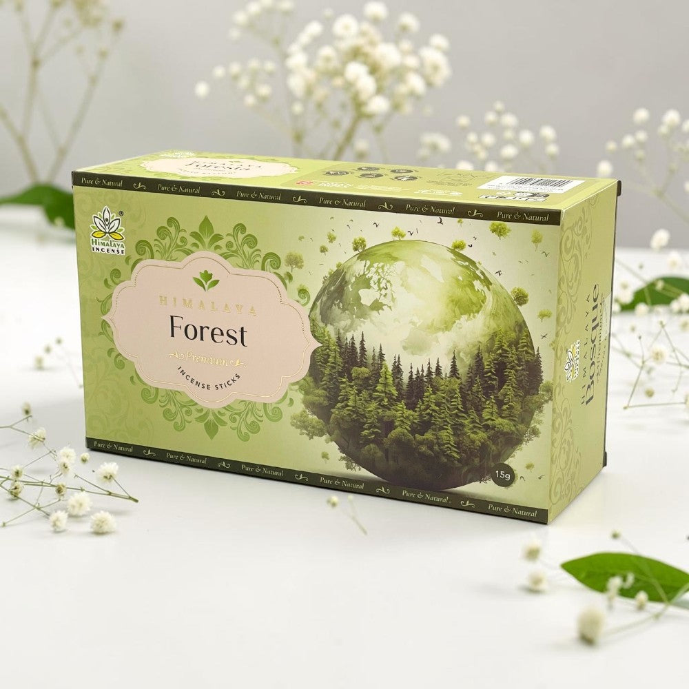 A box of Himalaya Forest Organic Turmeric Stethosan incense sticks, styled on a white surface with small white flowers and green leaves in the background.