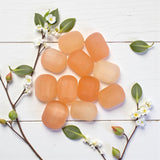 peach selenite tumbles on white wood 