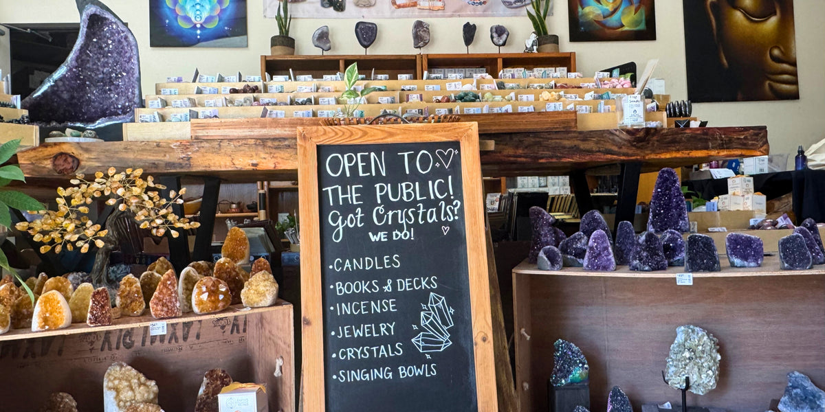 Crystal shop with various crystals and a chalkboard sign welcoming the public.